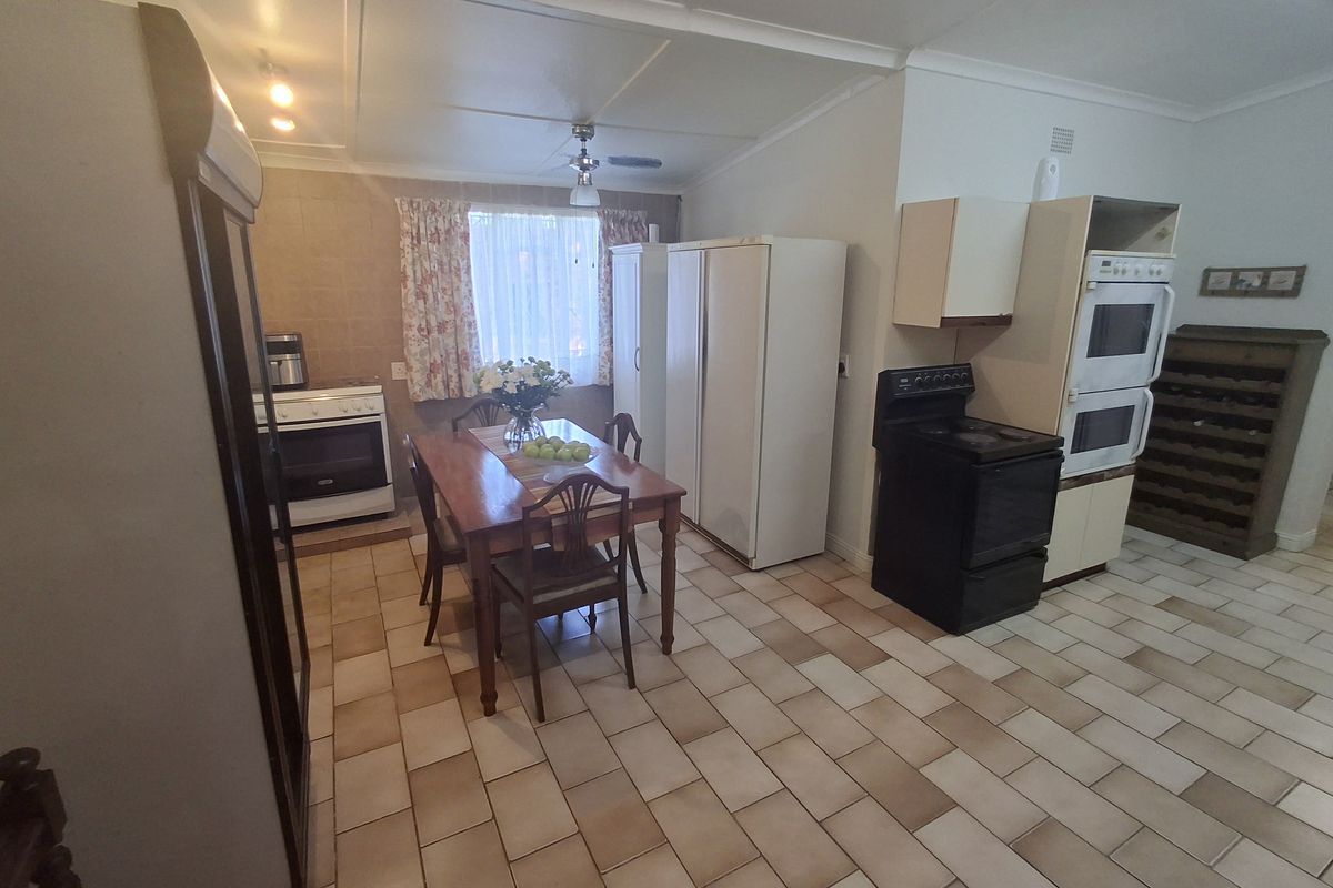 A dated kitchen area featuring tiled flooring, built-in oven and hob, and basic cabinetry, offering potential for a modern renovation.
