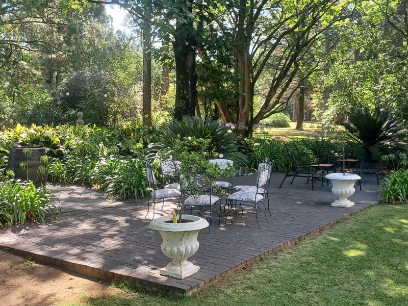 A spacious paved patio area set within a lush, mature garden, providing a serene outdoor entertainment space.