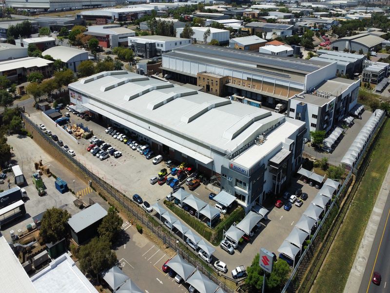Aerial view of a large industrial warehouse facility featuring extensive parking, shade cloth carports, and professional commercial infrastructure.