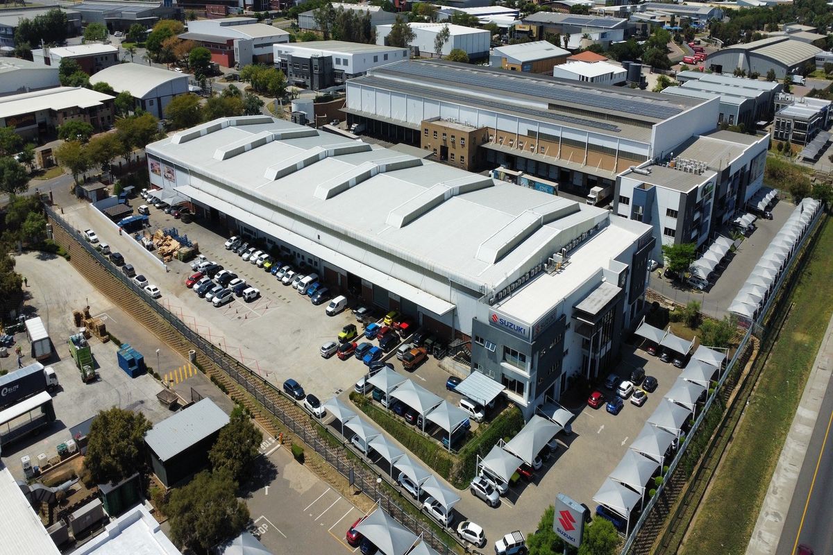 Aerial view of a large industrial warehouse facility featuring extensive parking, shade cloth carports, and professional commercial infrastructure.
