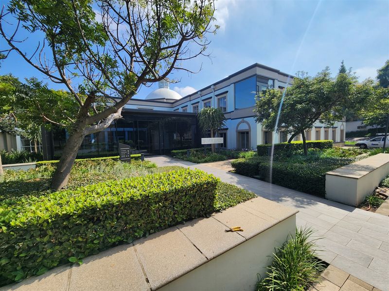 Front exterior view of the Silver Birch office building featuring a modern glass entrance, manicured gardens, and a distinctive architectural dome.