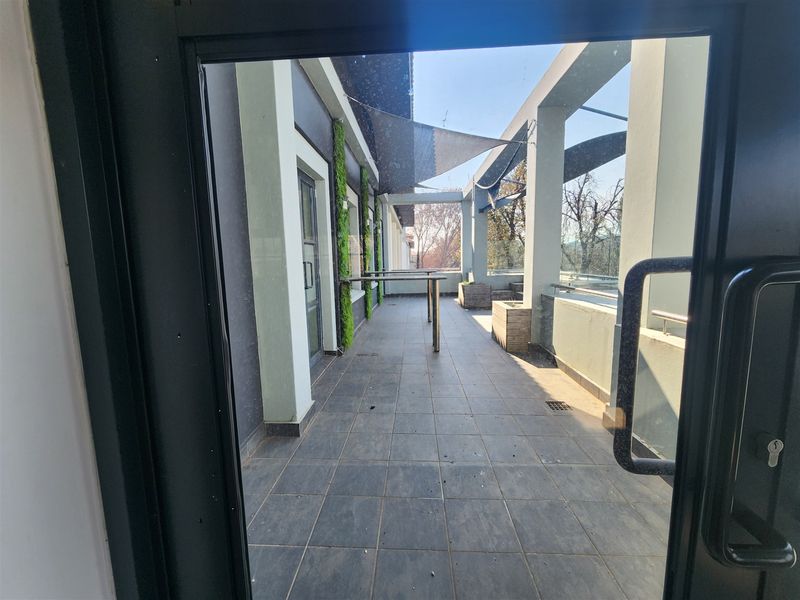 A spacious outdoor balcony featuring tiled flooring, a vertical garden wall, shade sail, and built-in planters, offering a functional exterior space.