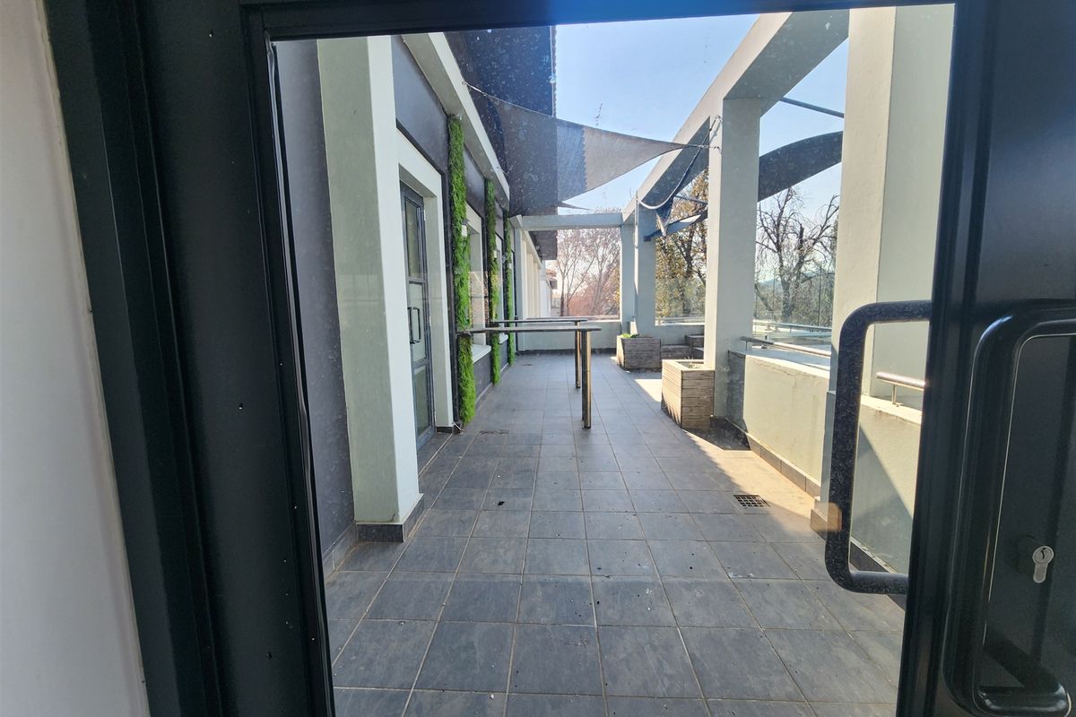 A spacious outdoor balcony featuring tiled flooring, a vertical garden wall, shade sail, and built-in planters, offering a functional exterior space.