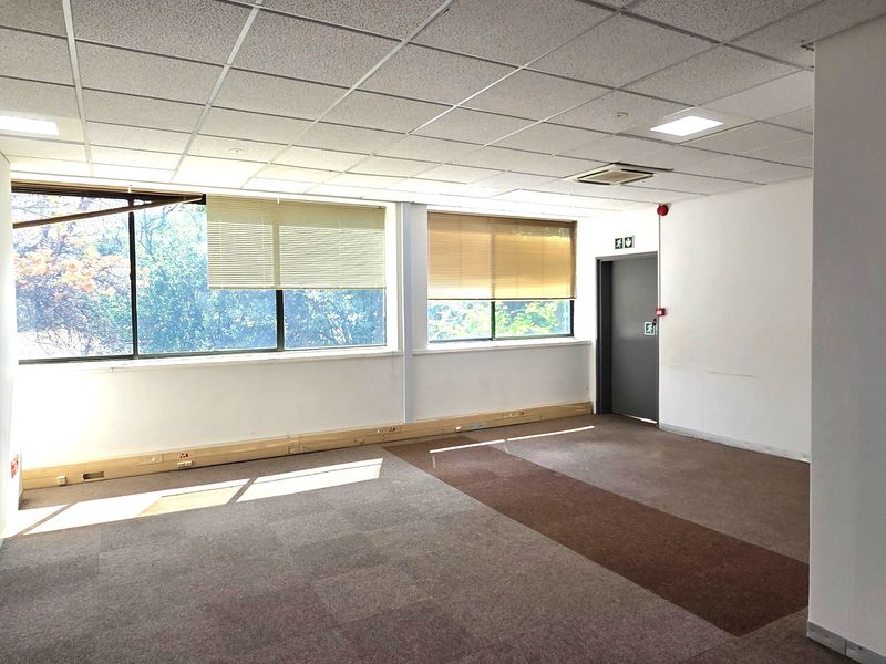 An empty, open-plan office space featuring suspended ceilings, recessed lighting, carpet tiles, and perimeter trunking for electrical and data connectivity.