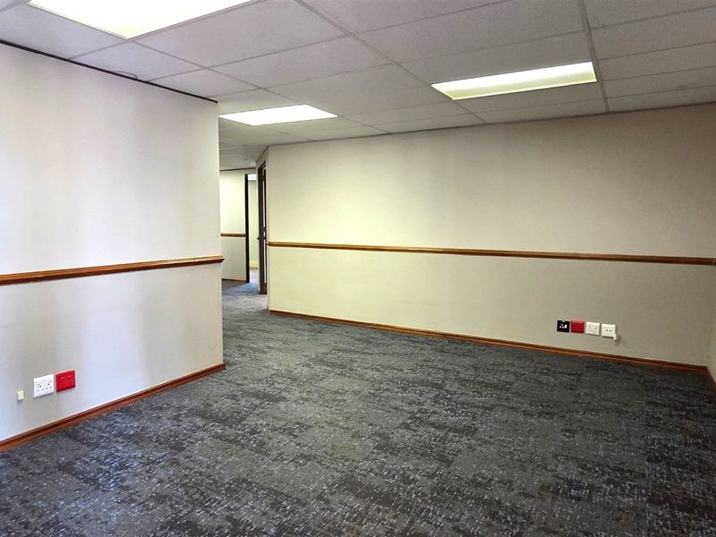 A clean, empty office space featuring carpet tiles, a suspended ceiling with recessed lighting, and integrated electrical and data points.