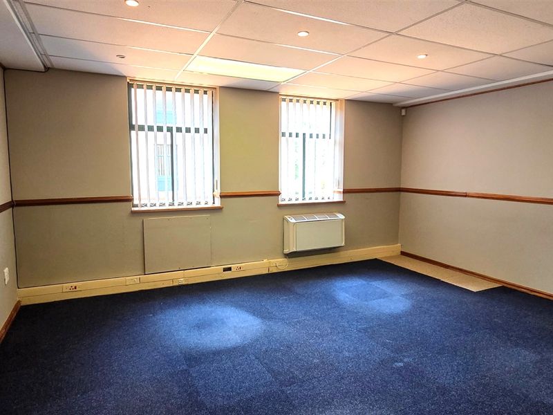 A vacant office space featuring a suspended ceiling, recessed lighting, HVAC unit, and carpeted flooring with neutral wall finishes.