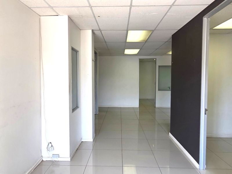 An empty office space featuring ceramic tile flooring, a suspended ceiling with recessed lighting, and an internal partition wall.