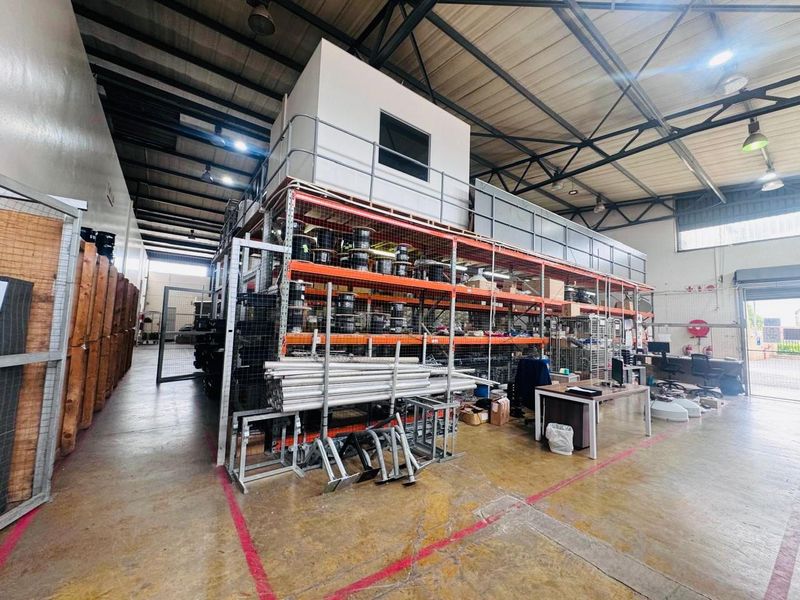Spacious industrial warehouse featuring a mezzanine level, heavy-duty steel racking systems, exposed roof trusses, and durable concrete flooring suitable for storage or operations.