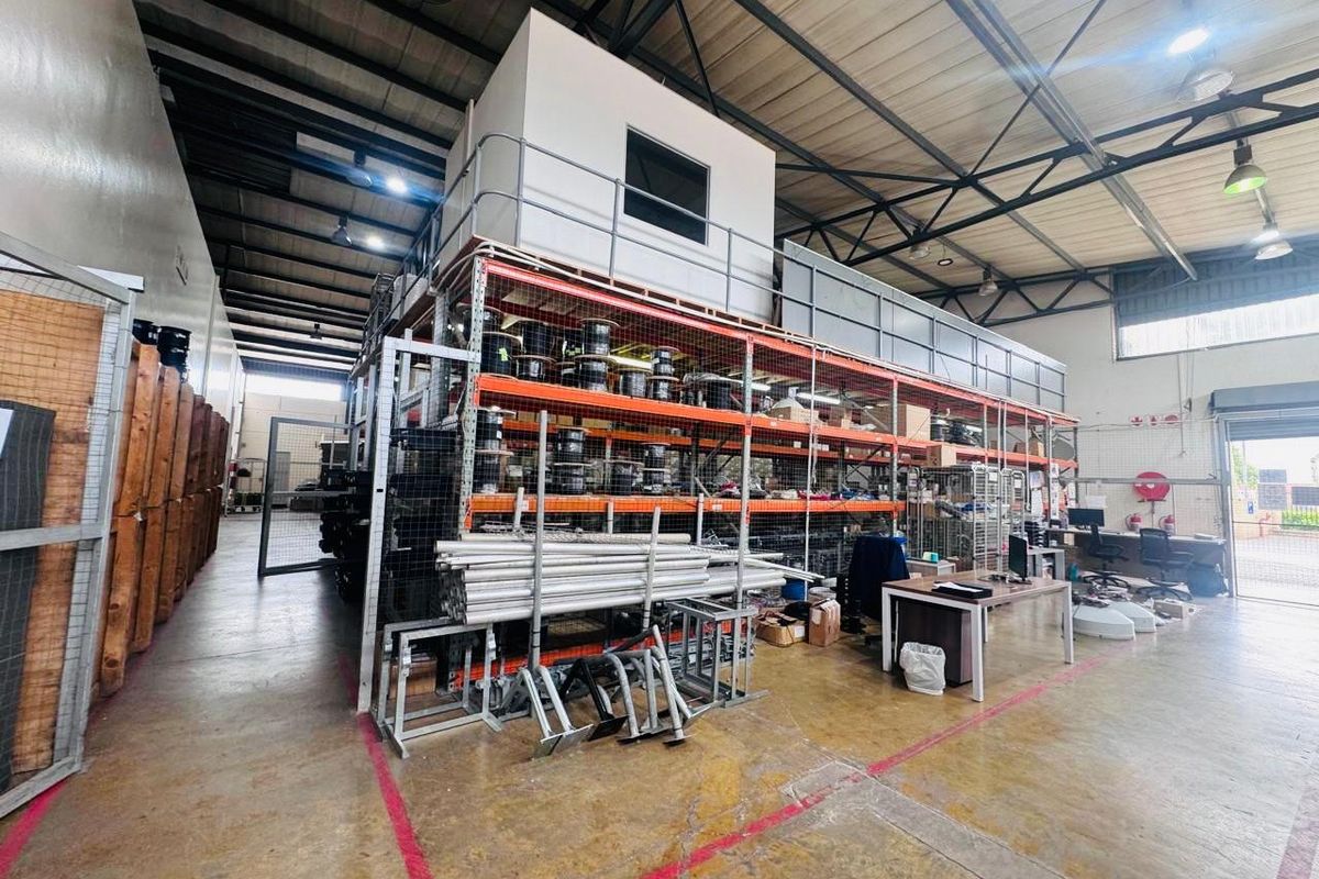 Spacious industrial warehouse featuring a mezzanine level, heavy-duty steel racking systems, exposed roof trusses, and durable concrete flooring suitable for storage or operations.