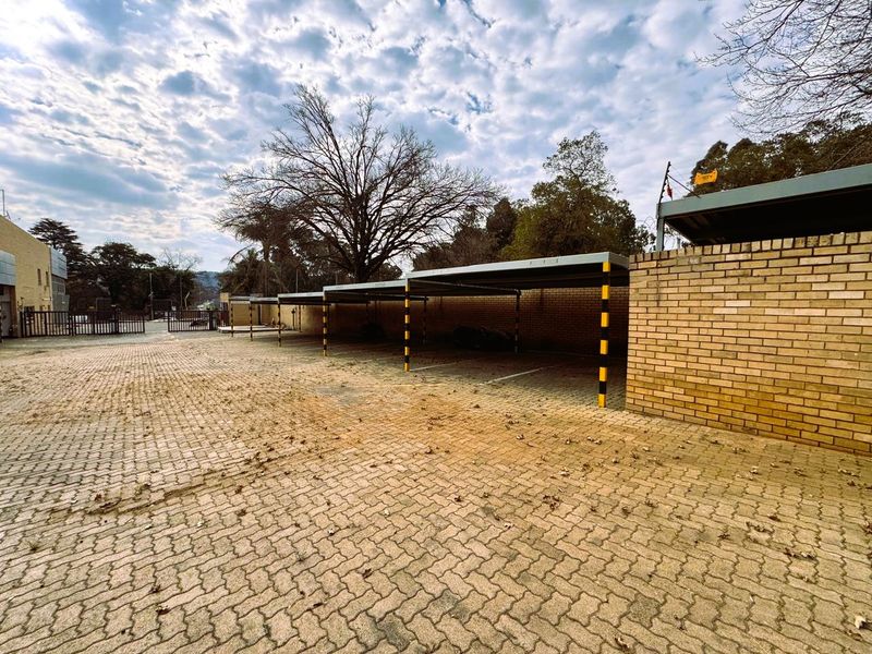 Outdoor covered parking area featuring multiple bays with brick walling, paved surfacing, and perimeter electric fencing.