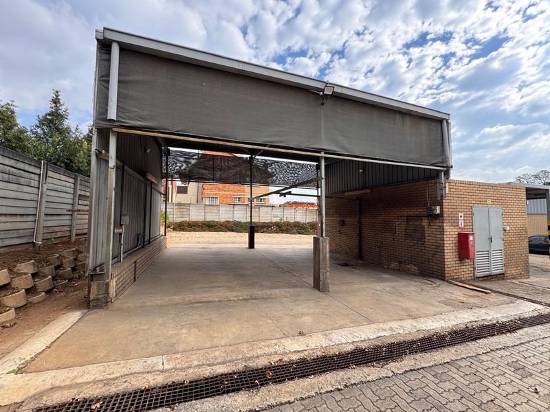 Open-plan outdoor utility or service area featuring a concrete slab, metal roof structure, and brick masonry walls, suitable for various commercial or storage purposes.