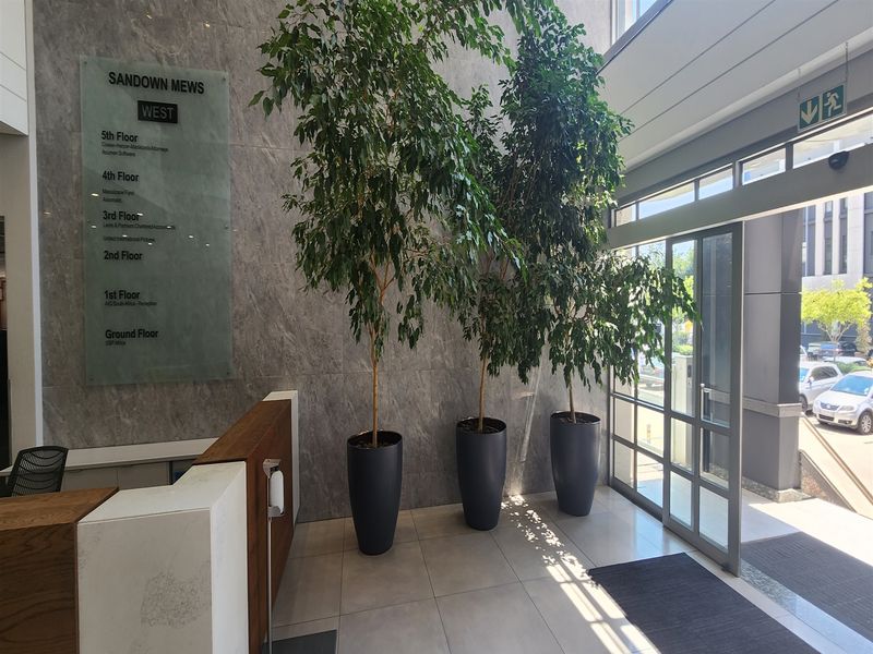 Modern office building entrance lobby featuring marble wall cladding, a professional directory board, and a reception desk with glass door access.