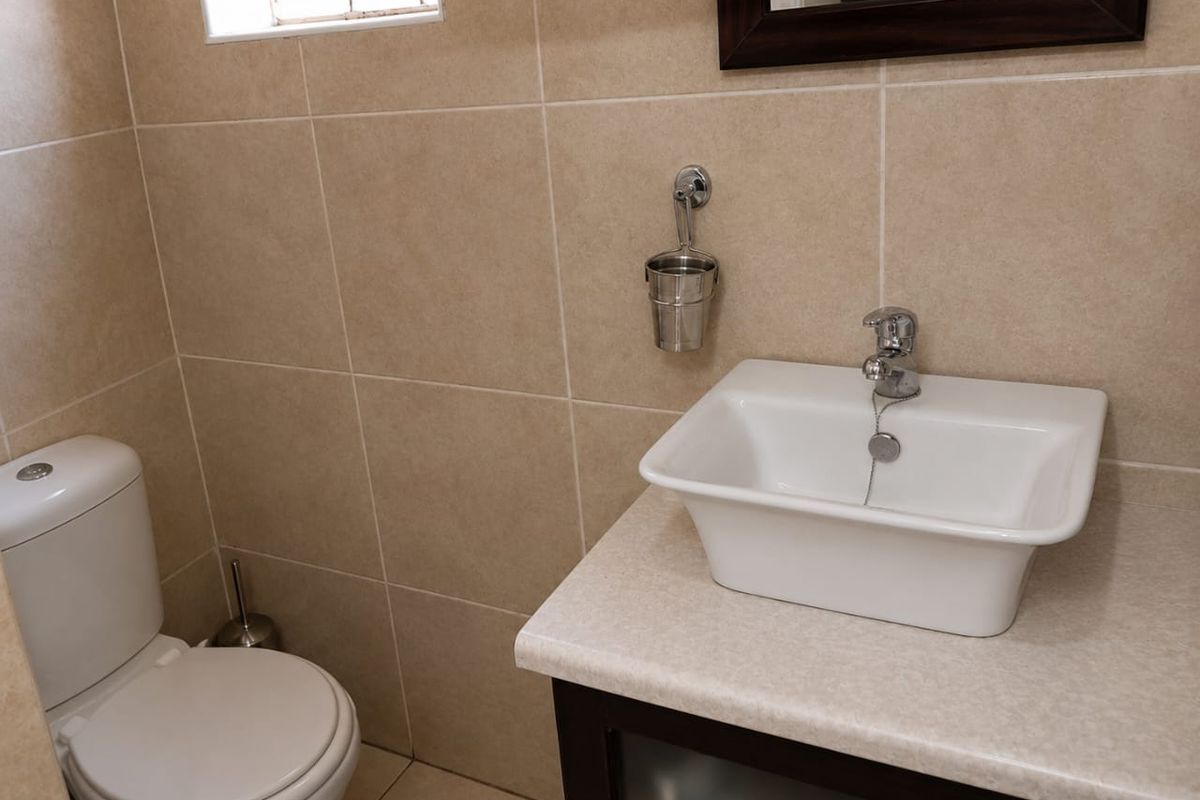 A clean, modern bathroom featuring neutral wall tiles, a vanity cabinet with a countertop basin, and a standard toilet.