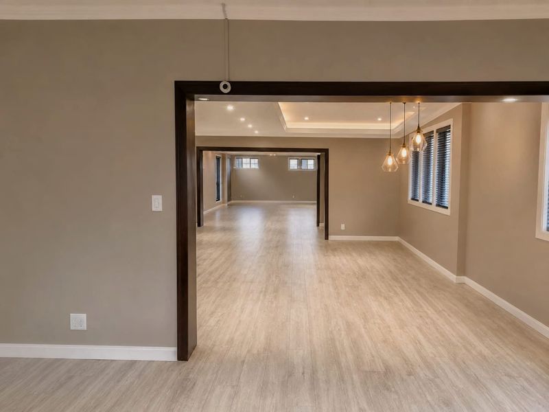 Spacious open-plan retail area featuring modern laminate flooring, recessed tray ceiling lighting, and neutral wall tones, providing a versatile and well-lit commercial space.