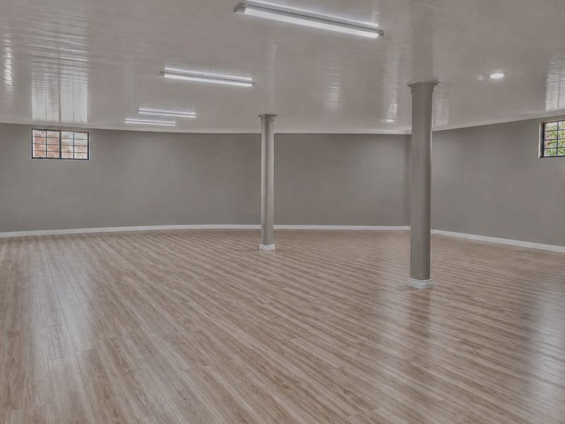 A spacious, open-plan retail or commercial area featuring modern laminate flooring, structural columns, and bright overhead lighting, offering a versatile blank canvas.