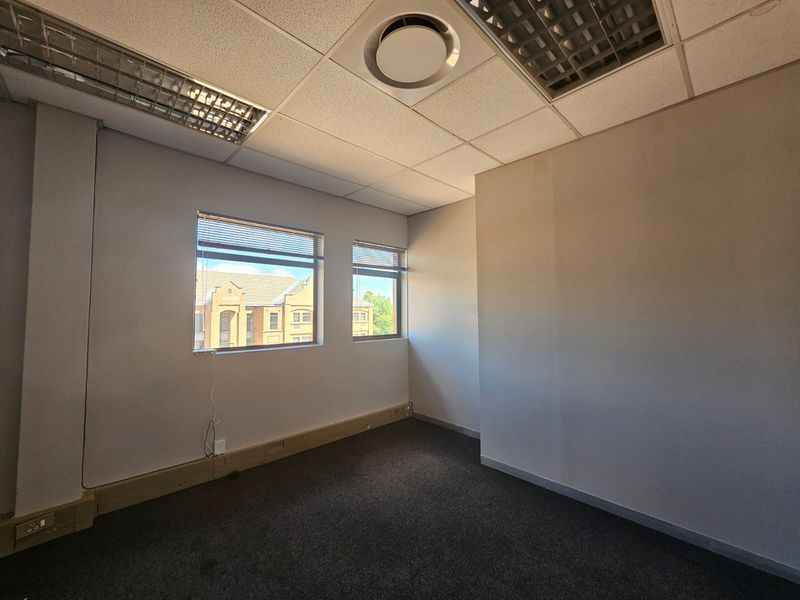 A vacant office space featuring a suspended ceiling, recessed lighting, air conditioning, and carpeted flooring with integrated electrical trunking.
