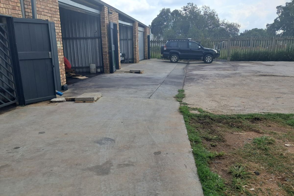 Industrial property exterior featuring multiple garage bays with brick facade and a large concrete yard area.