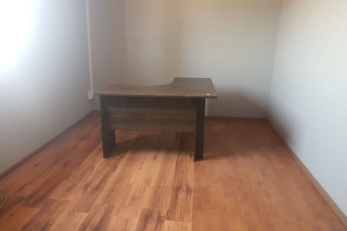 A simple office space featuring wood-look laminate flooring and neutral wall finishes, suitable for a functional workspace.