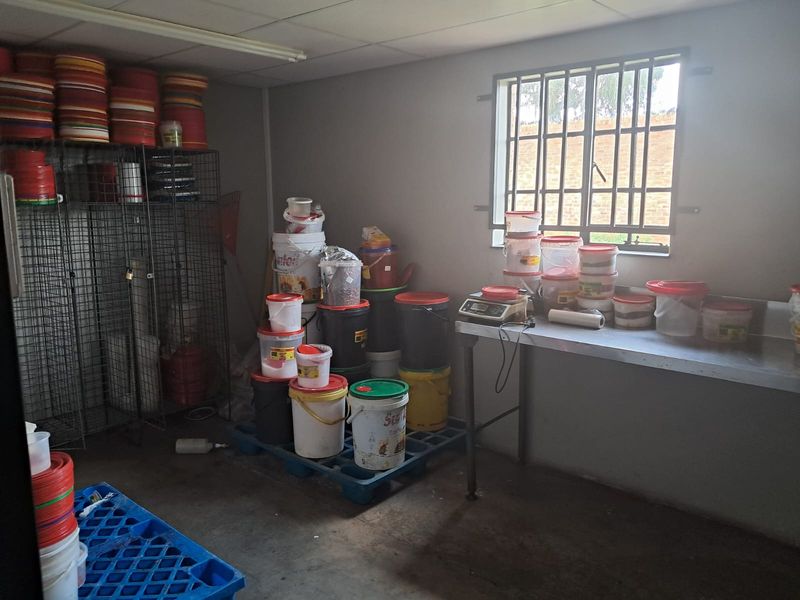 A functional industrial utility space featuring a stainless steel prep table, security window bars, and ample storage capacity for operational supplies.