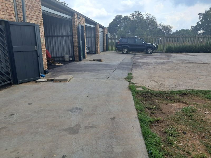 Industrial property exterior featuring multiple garage bays with brick facade and a large concrete yard area.