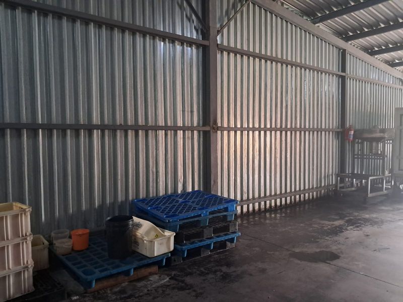Industrial warehouse space featuring corrugated metal wall cladding, exposed steel structural framing, and durable concrete flooring.