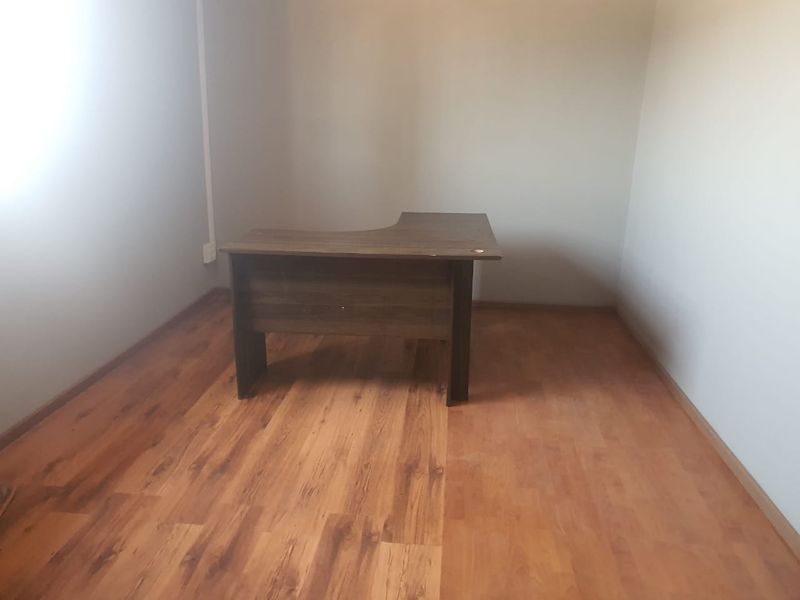 A simple office space featuring wood-look laminate flooring and neutral wall finishes, suitable for a functional workspace.