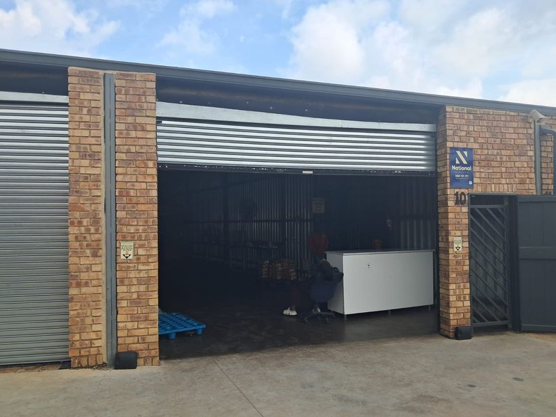 Industrial unit featuring a large roller shutter door entrance, face brick facade, and concrete flooring, suitable for storage or workshop operations.
