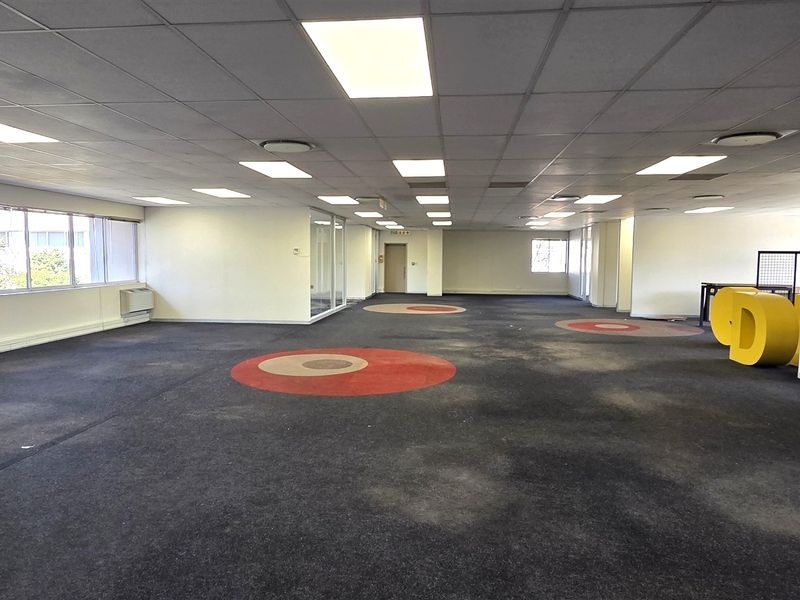 Spacious open-plan office area featuring a suspended ceiling, recessed lighting, glass partitioning, and an air conditioning unit, ready for custom fit-out.