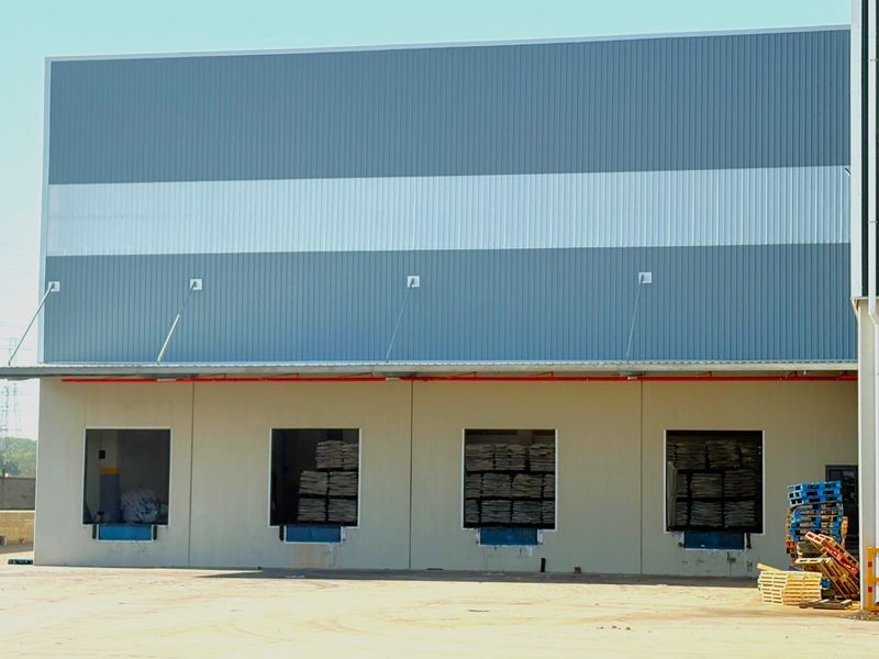 Industrial warehouse exterior featuring multiple loading docks with metal cladding and a concrete hardstand area.