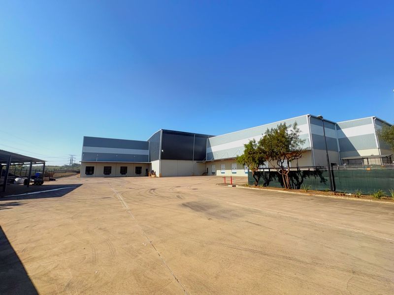 Wide-angle view of an industrial warehouse facility featuring a large concrete yard, multiple loading bays, and modern metal cladding exterior.