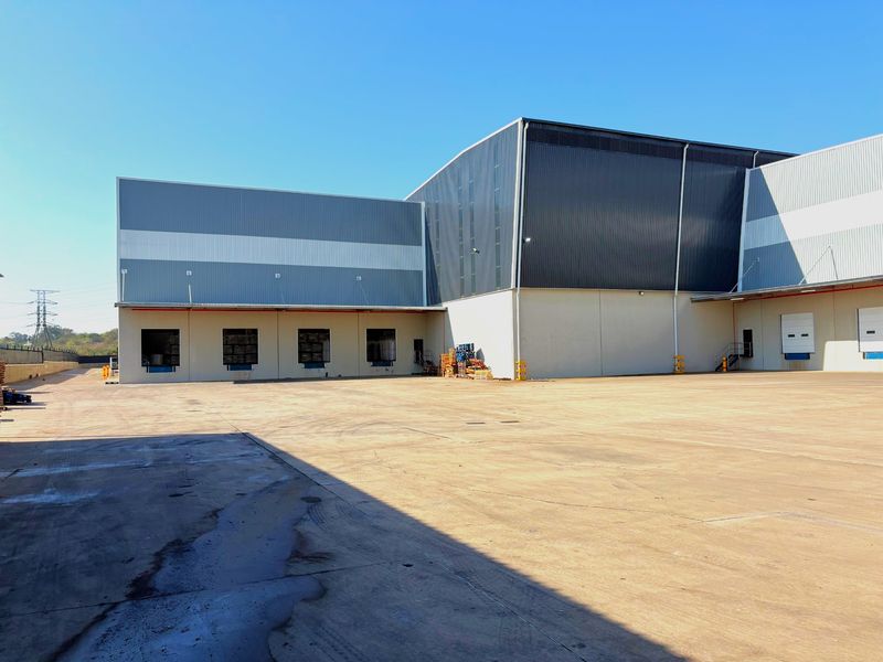 Industrial warehouse exterior featuring a large concrete yard, multiple loading docks, and modern metal cladding facade.