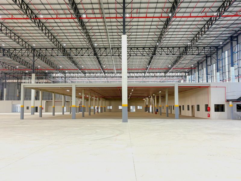 Spacious industrial warehouse featuring a high-clearance steel truss roof, integrated fire sprinkler system, concrete mezzanine level, and polished concrete flooring.