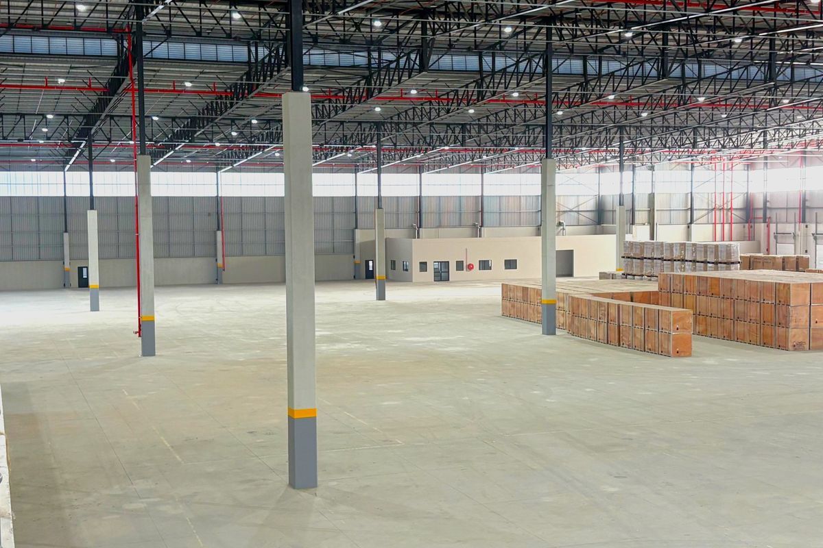 Spacious industrial warehouse featuring high ceilings with exposed steel trusses, fire sprinkler system, polished concrete floors, and integrated internal office space.