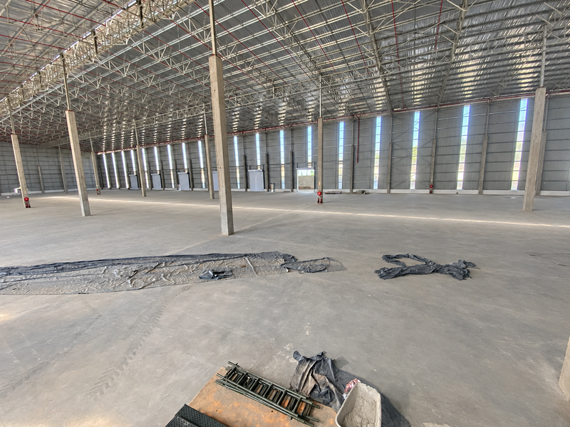 A large, open-plan industrial warehouse space featuring high ceilings, concrete flooring, and robust steel structural supports, suitable for storage or manufacturing operations.