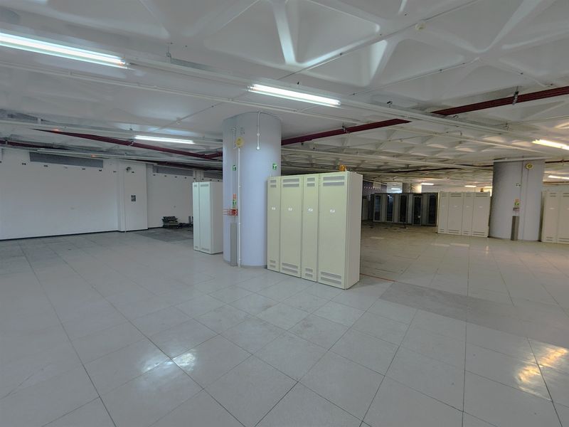 Spacious open-plan office area featuring a distinctive waffle ceiling, tiled flooring, and integrated server cabinetry, suitable for a versatile commercial workspace.