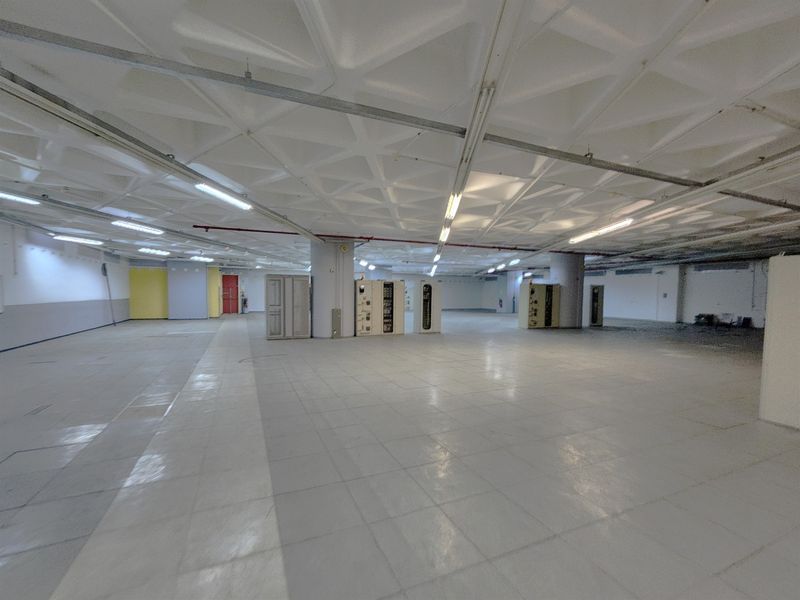 A large, open-plan office space featuring a distinctive waffle slab ceiling, tiled flooring, and structural columns, offering a versatile layout for commercial use.