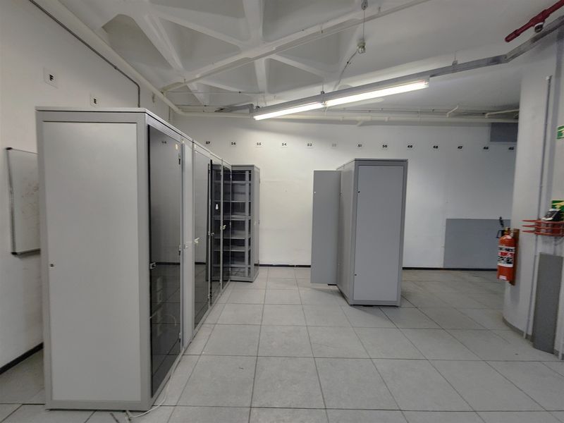 A functional utility or server room featuring raised flooring, exposed ceiling structure, and multiple integrated server racks for technical infrastructure.