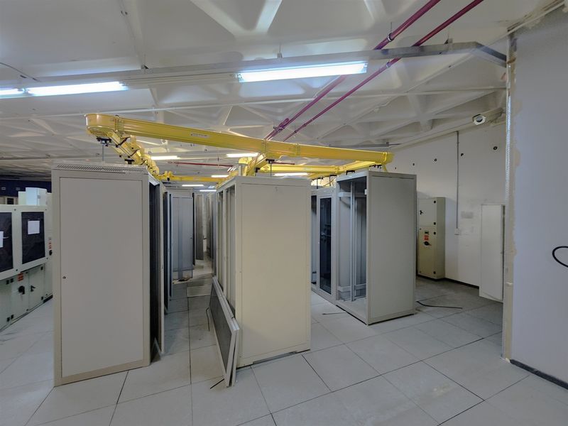 A functional server room or utility space featuring raised flooring, overhead cable management, and multiple server rack enclosures.