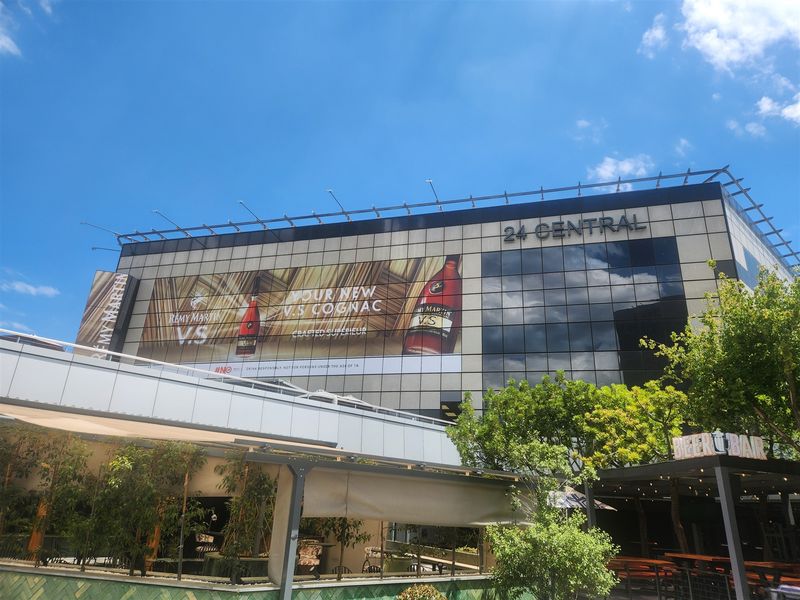 Exterior view of the 24 Central office building featuring modern glass facade, metal cladding, and prominent commercial signage.