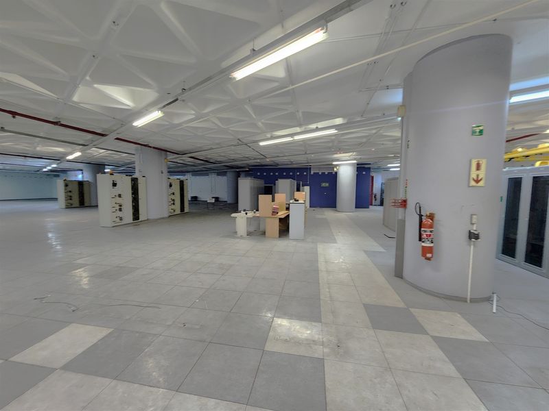 A spacious, open-plan office area featuring a distinctive waffle ceiling, tiled flooring, and integrated electrical infrastructure, suitable for a flexible workspace layout.