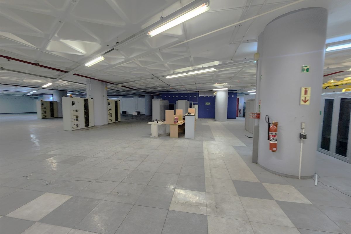 A spacious, open-plan office area featuring a distinctive waffle ceiling, tiled flooring, and integrated electrical infrastructure, suitable for a flexible workspace layout.