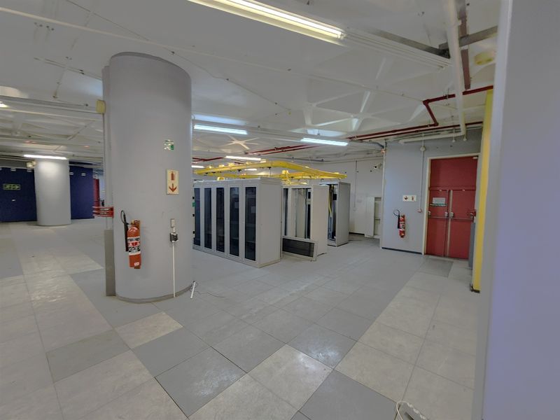 A functional utility and server room featuring industrial overhead cable management, tiled flooring, and secure fire-rated access doors.