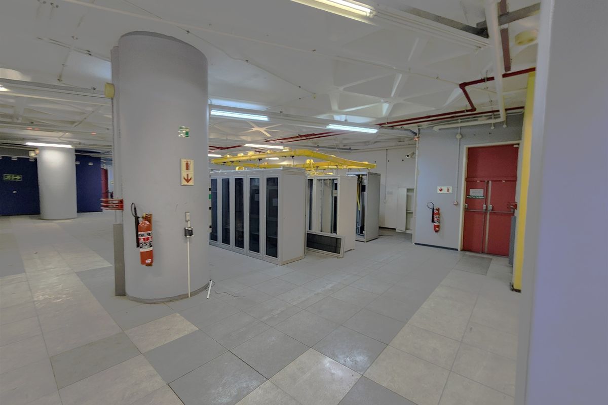A functional utility and server room featuring industrial overhead cable management, tiled flooring, and secure fire-rated access doors.