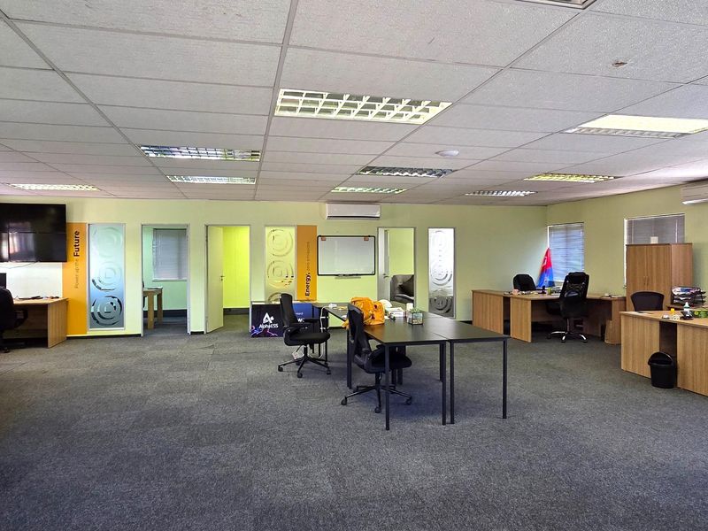 Spacious open-plan office area featuring suspended ceilings, recessed lighting, split-system air conditioning, and carpeted flooring with multiple partitioned office spaces.