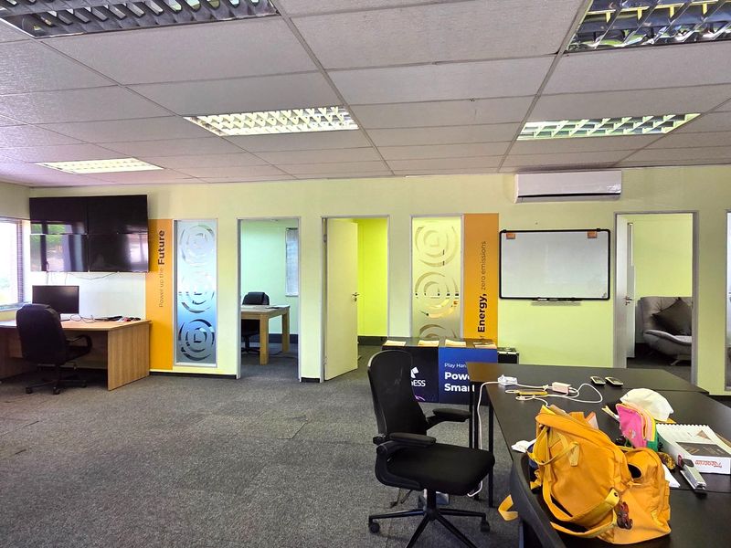 Open-plan office space featuring suspended ceilings, recessed lighting, split-system air conditioning, and multiple private office access points with frosted glass detailing.