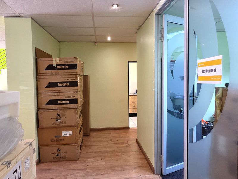 Office hallway featuring laminate flooring, recessed ceiling lighting, and a frosted glass door leading to a testing desk area.
