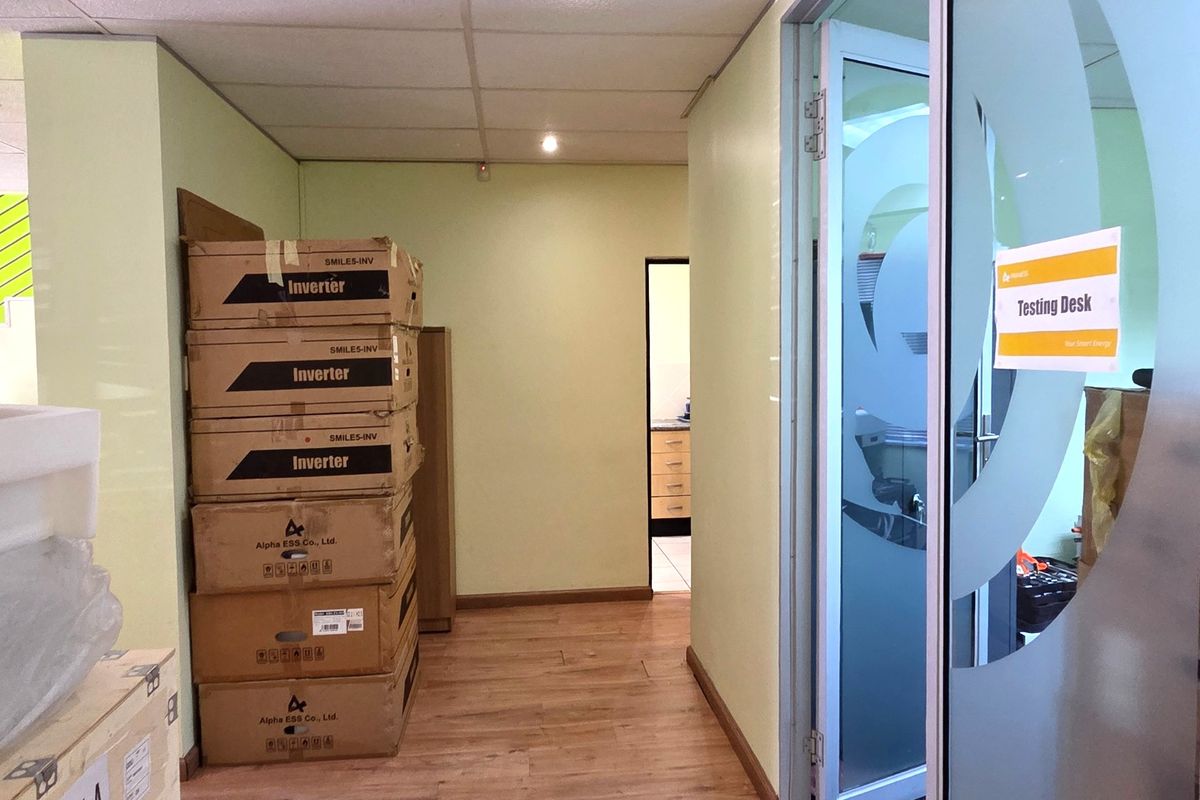 Office hallway featuring laminate flooring, recessed ceiling lighting, and a frosted glass door leading to a testing desk area.