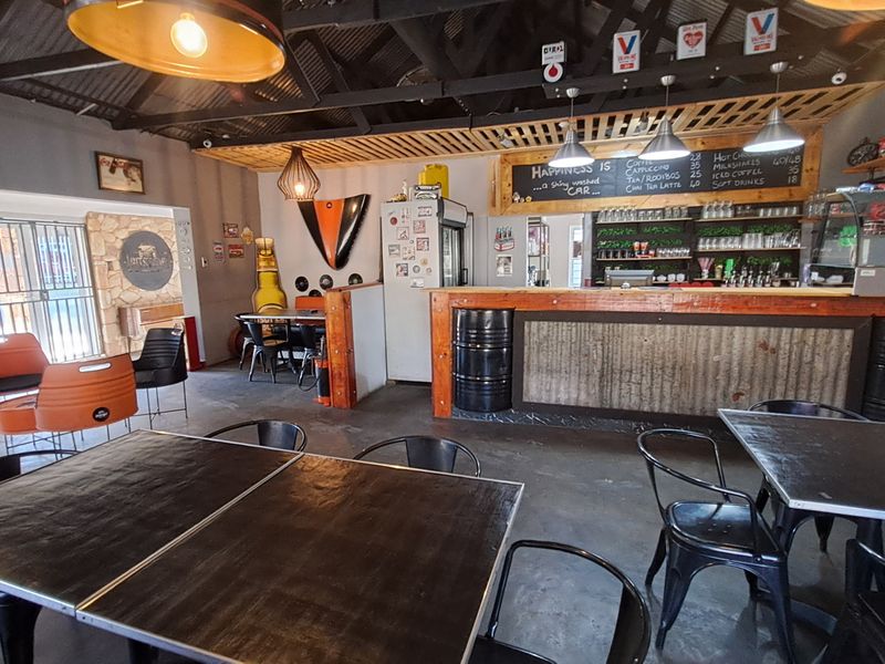 A rustic-style bar area featuring a built-in counter with corrugated metal cladding, exposed roof trusses, and a stone feature wall.