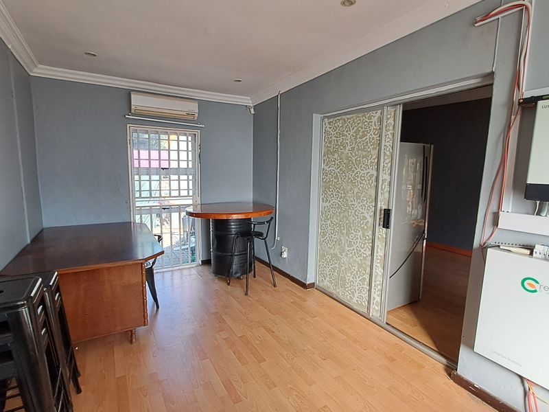 Office space featuring laminate flooring, air conditioning, and integrated solar power infrastructure with inverter and battery storage system.