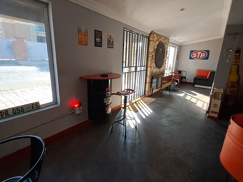 A themed bar area featuring a stone accent wall, concrete flooring, and secure metal gate access.
